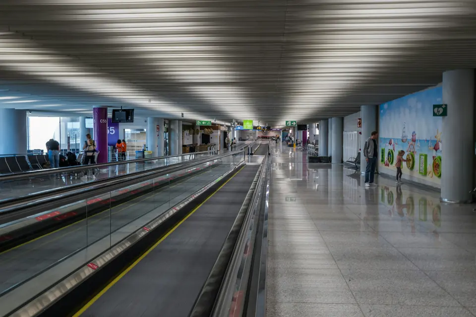Flyplassterminal med rullende fortau og et barn ved en veggmaling