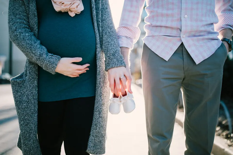 Gravid kvinne og mann holder et par små babysko