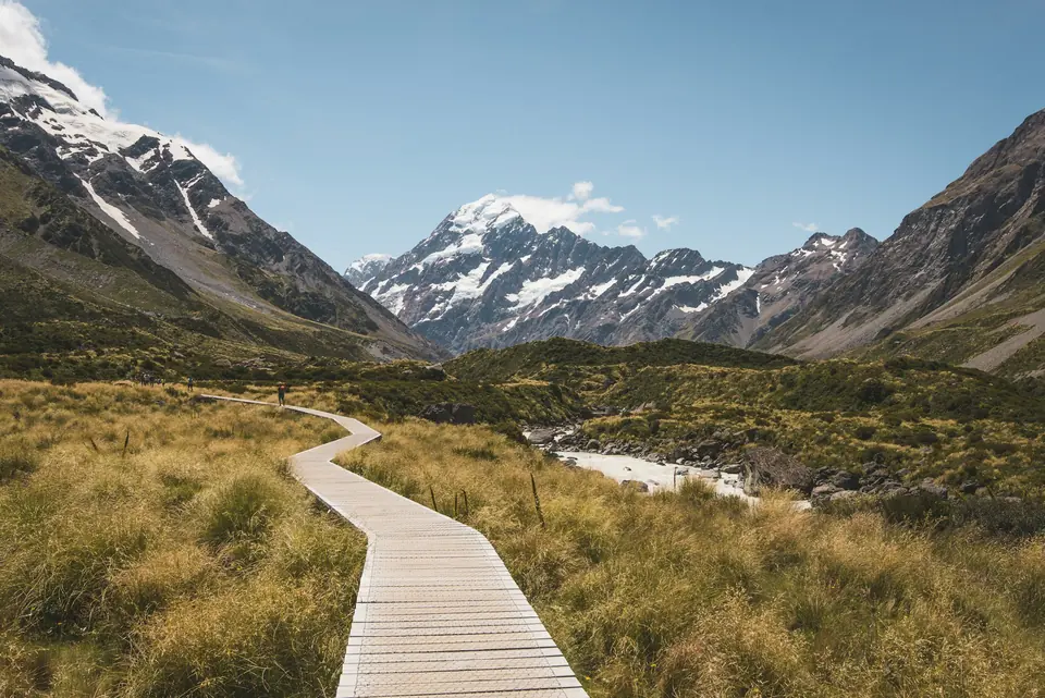 Tregangvei gjennom dalen mot snødekt fjell på New Zealand